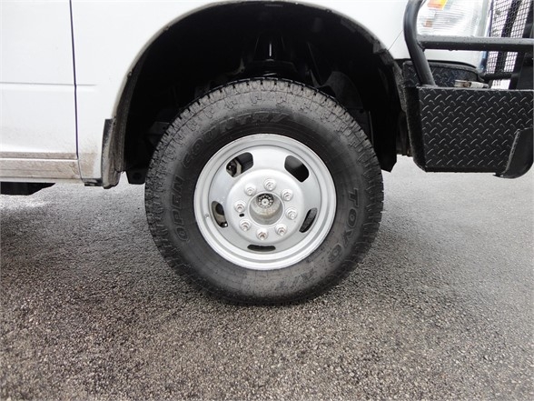 Truck wheel and tire showing Goodyear Wrangler tire on front of white 2012 Ram 3500 SLT dump truck with metal step and fender.