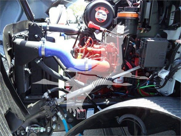 Mack MD6 engine bay showing blue coolant hose, red engine components, air intake, wiring harness, and various labels.
