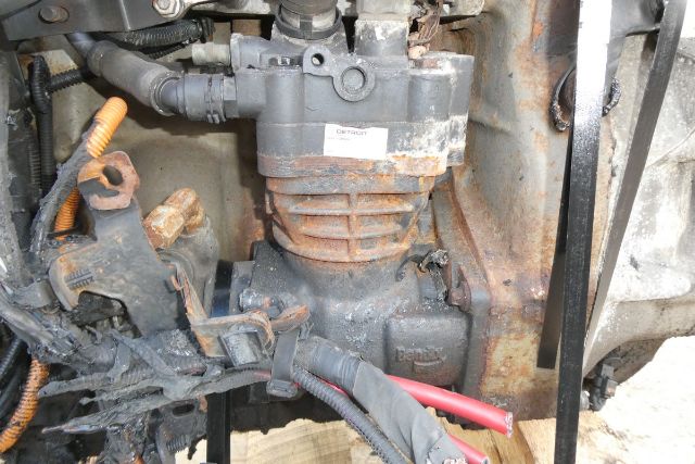 Detroit DD15 engine core showing intake manifold, valve cover, and wiring harnesses with rust and grime on surrounding components.