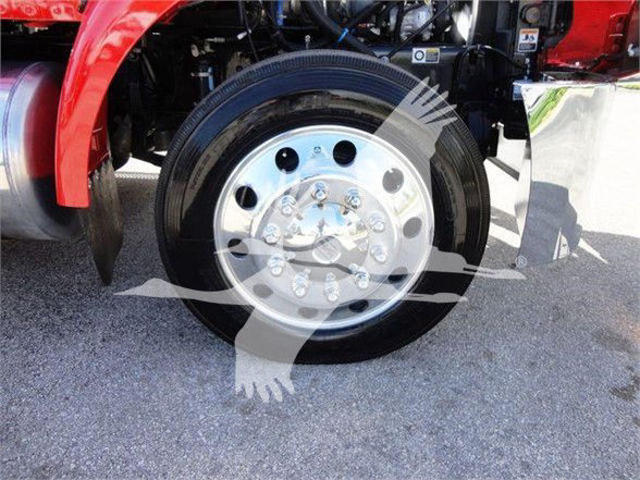 Peterbilt 337 front wheel and fender area with polished aluminum wheel and black tire. Visible undercarriage components and red body panel.