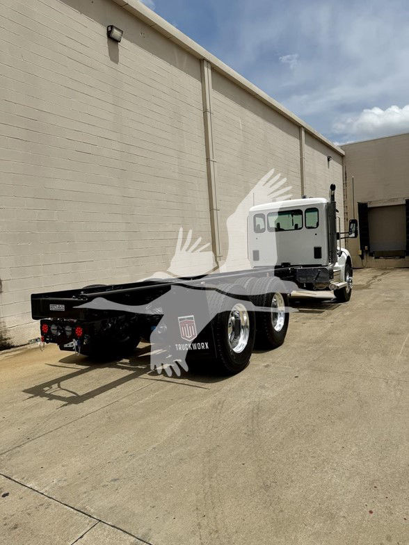 Kenworth T480 chassis cab shown from rear-left side with white cab, dual rear axles, black frame, and mudflaps.