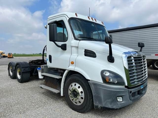 Truck cab and front-end view of a white 2015 Freightliner Cascadia conventional daycab. Visible text includes no specific labels on the cab in the image.