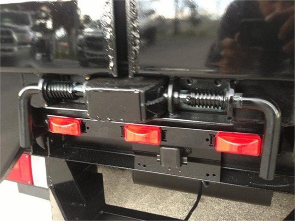 Back view of a 2024 Advanced Fabricators 14 FT dump body showing lift mechanism with two red taillights and a mounting bracket.