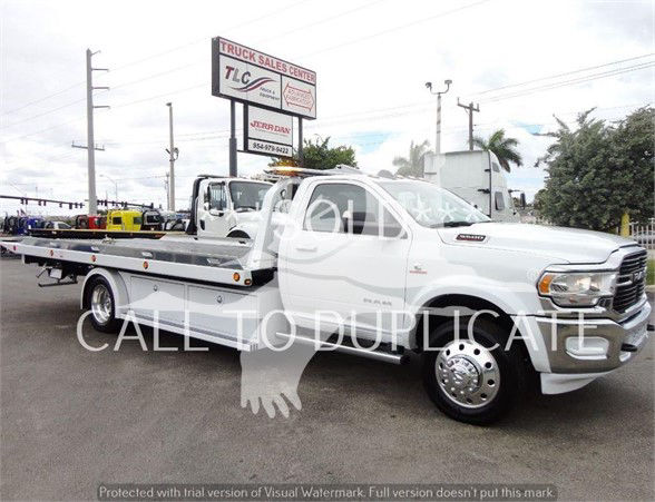 2023 Ram 5500 HD SLT tow truck side view with white cab and flatbed, dealership watermark across image.