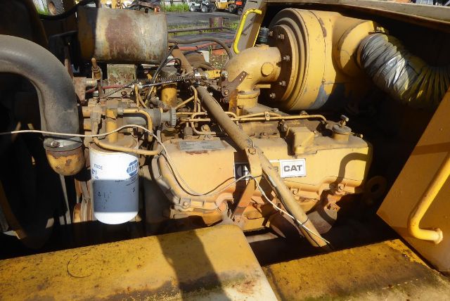 Caterpillar V225 engine bay showing CAT engine with oil filter and hoses in a yellow industrial machine.