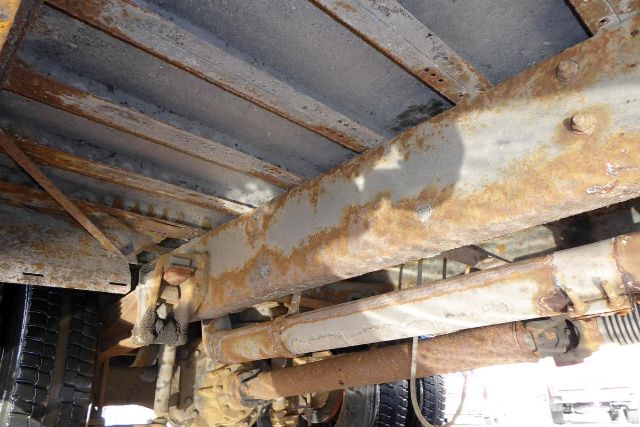 Underbody view of a 2002 Freightliner FS65 chassis showing rusted frame members and suspension components.
