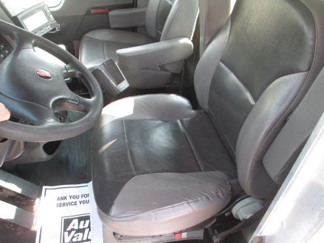 Truck interior showing black leather seats, steering wheel, and center console in Kenworth cab.