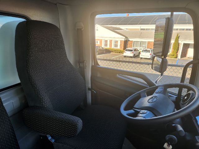 Interior of a 2025 Hino L6 truck cab showing steering wheel, driver's seat, and dashboard from passenger side window view.