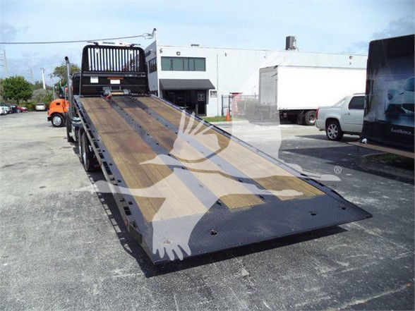 Kenworth T880 tow truck flatbed with ramp extending; no close-up readable text visible on parts.