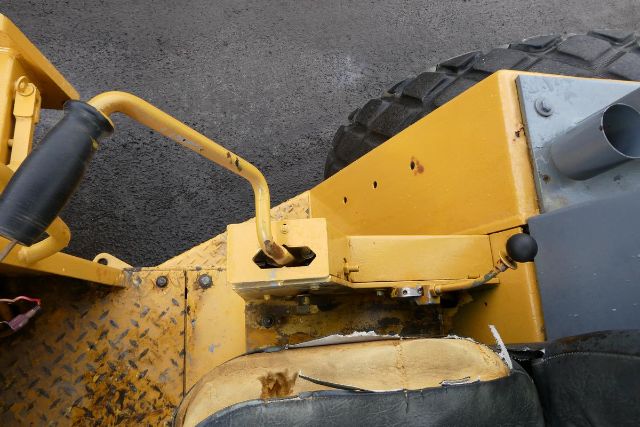 Bomag BW212D-2 wheel/track machinery showing yellow paint, lever, and hydraulic linkage near seat and tire.