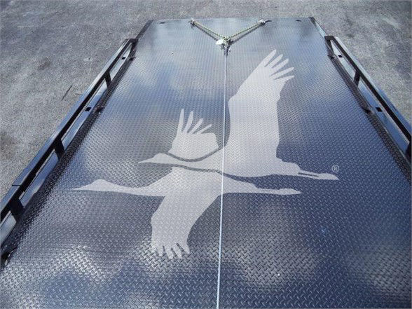 Diamond plate trailer deck with a large white crane graphic centered; no visible text.