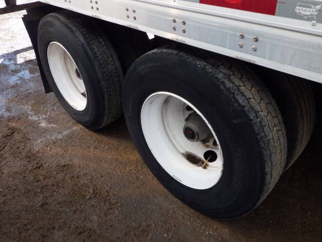 Dual rear trailer tires on a 2014 Wabash dry van trailer, white rims, mud and dirt on ground.