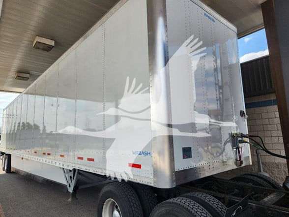 White Wabash trailer under a shelter showing side and front with wheel, undercarriage, and hitch; branding visible: WABASH near rear.