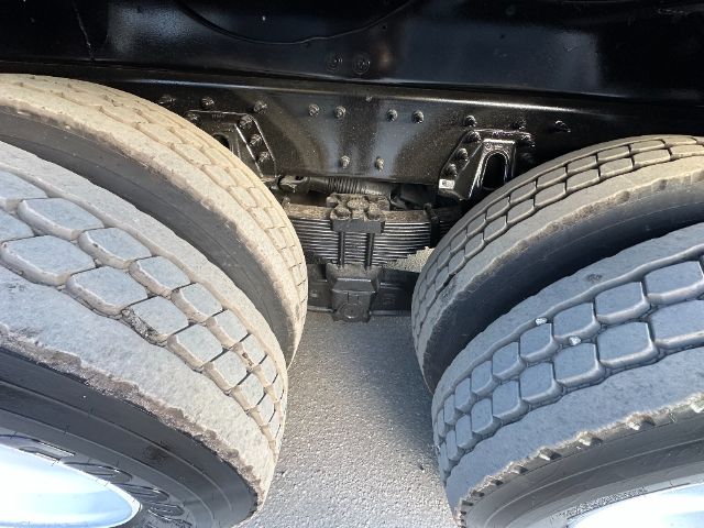 Twin rear tractor axles with suspension and linkage under a truck chassis, showing dual wheels and crossmember.