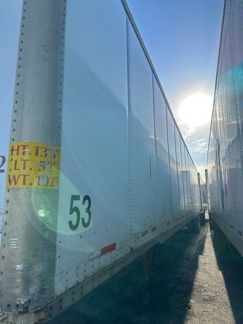 Trailer side of a white Wabash Duraplate trailer with the number 53 and a yellow weight sticker visible.