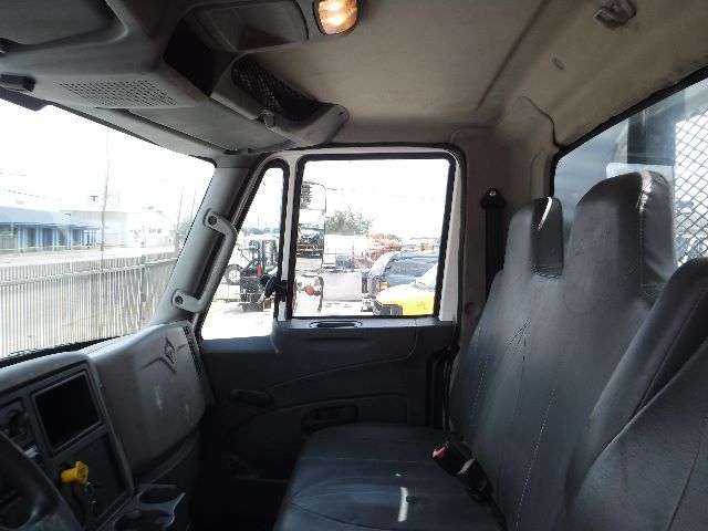 Truck cab interior with two front seats and dashboard visible, side window and door window, light from outside.