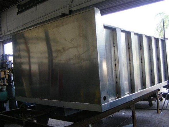 A 12 ft dump body metal truck bed mounted on a frame inside a workshop.