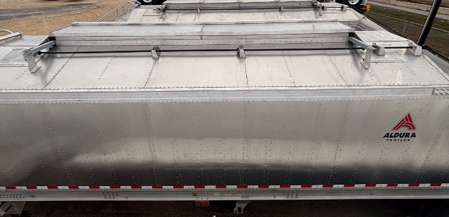 Aluminum hopper trailer side showing Aldura logo, flat top with locking hatches and riveted seams.
