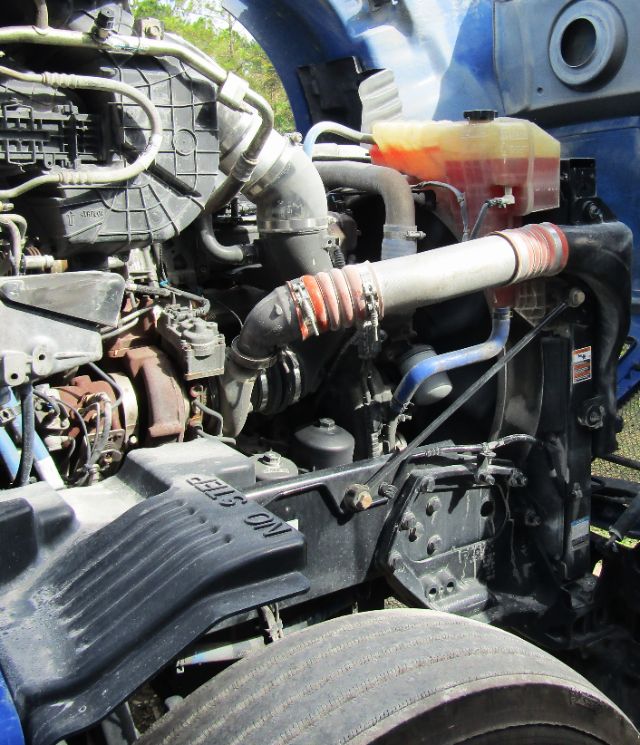Kenworth T680 engine bay showing coolant reservoir, hoses, and air intake components.