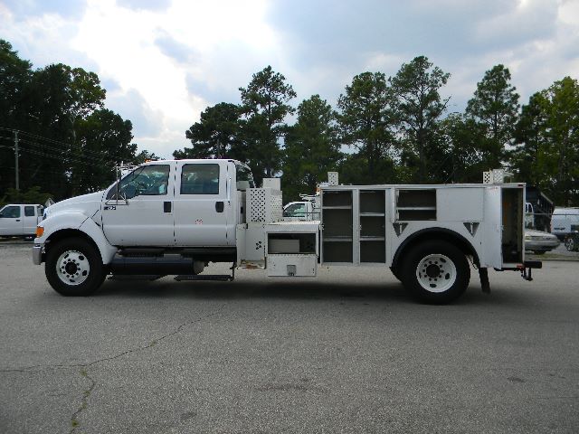 Service/utility truck showing white Ford F-750 Super Duty crew cab with utility body and compartments.