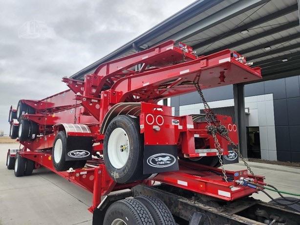Chassis trailer with red Cheetah ISO Tank frame and white wheel rims, mounted on a low bed trailer, showing hydraulic arms and trailing equipment.