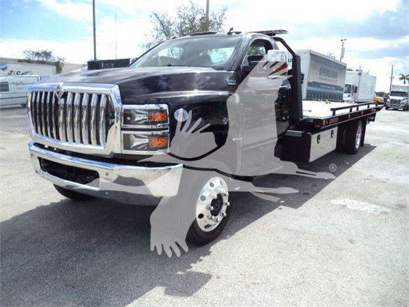 Tow truck with a black cab and a flatbed, front grille chrome, large chrome bumper, wheel, and partially visible doors.