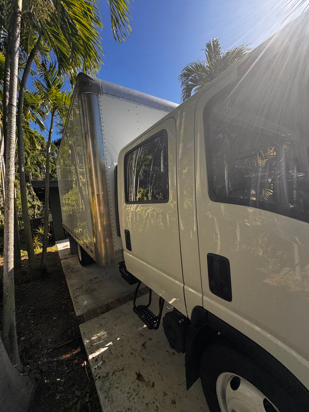 Isuzu NQR box truck side view showing cab and attached aluminum box trailer with steps and window on door.