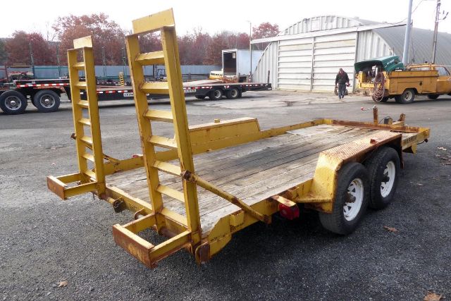 Trailer: dual-axle flatbed trailer with loading ramps in yellow, used condition.
