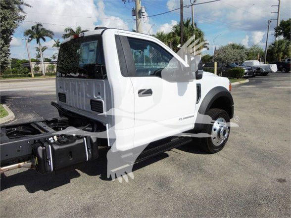 Ford F-550 chassis cab/ dump truck in white, side view showing cab and front wheel, no dump body attached in image.