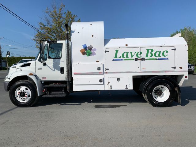 Truck side view with 'Lave Bac' logo on the utility body and various compartments; cab shows International branding.