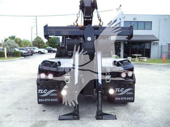 Tow truck rear view showing hydraulic arm and stabilizing legs, TLC decals, and contact numbers on the mud flaps.