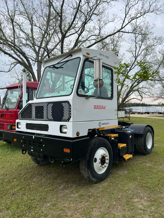 Capacity TJ 5000 yard truck tractor cab front view showing white cab with black grille and large windows, yellow steps, and heavy black chassis.
