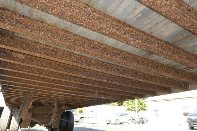 Trailer undercarriage and frame rails showing rusted crossmembers and bottom of a Fruehauf FB9T248 trailer.