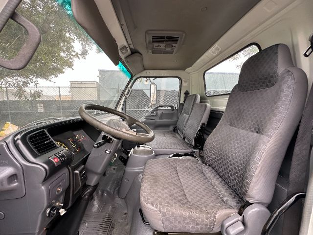 GMC W5500 interior showing front cabin with steering wheel, driver seat, and bench passenger seat; dashboard and controls visible.
