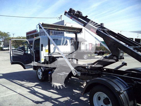 Isuzu NRR truck with mid-chassis tow truck lift in open lot showing cab doors open and hydraulic arm extended.