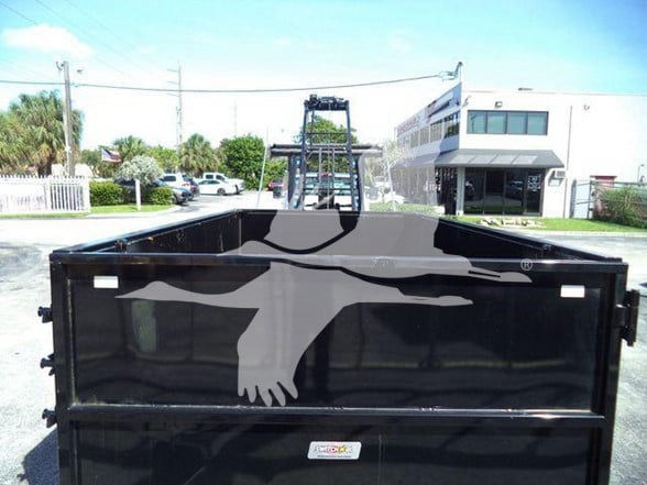 Back of a black dump truck bed on a 2023 Chevrolet Silverado 6500HD with hydraulic lift in a dealership lot.