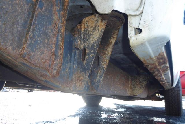 Underbody view of a 2011 Chevrolet 2500HD showing a rusted skid plate and frame support near the rocker panel.