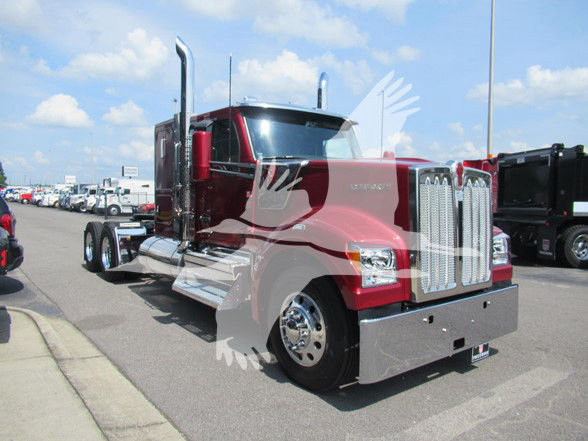 Kenworth W990 conventional sleeper truck in red with chrome grille and bumper, sitting in a lot.