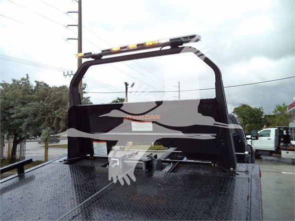 Ford F750 SD truck bed with roll-off platform and yellow warning lights on cab-back, viewed from rear on a tow truck bed.