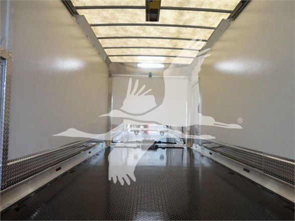 Inside empty Mack MD6 tow truck cargo area with diamond plate floor and overhead rails.