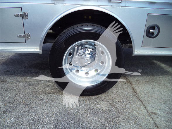 Wheel and fender area of a 2023 Ram 5500 SLT with chrome rim and flatbed body, partial graphic overlay visible.