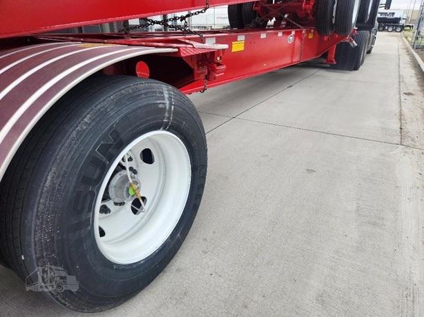 Chassis of a red Cheatah ISO Tank trailer showing a white wheel with black tire, dual-axle setup, and concrete surface.