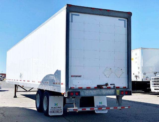 2015 Manac dry van trailer rear view showing roll-up doors, taillights, and mudflaps with MACRO Truck Sales contact info on the mudflaps and bottom bumper.