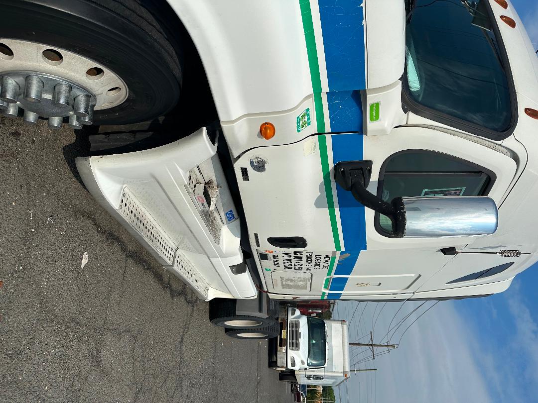 Truck cab of a white 2011 Freightliner Cascadia with blue and green stripes, chrome mirror, side steps, and logos visible.