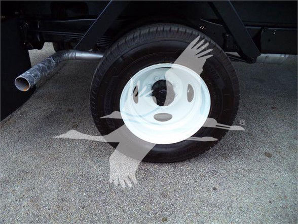 Flatbed truck wheel view showing single rear wheel with white steel rim and black tire; exhaust pipe visible and a watermark across the image.