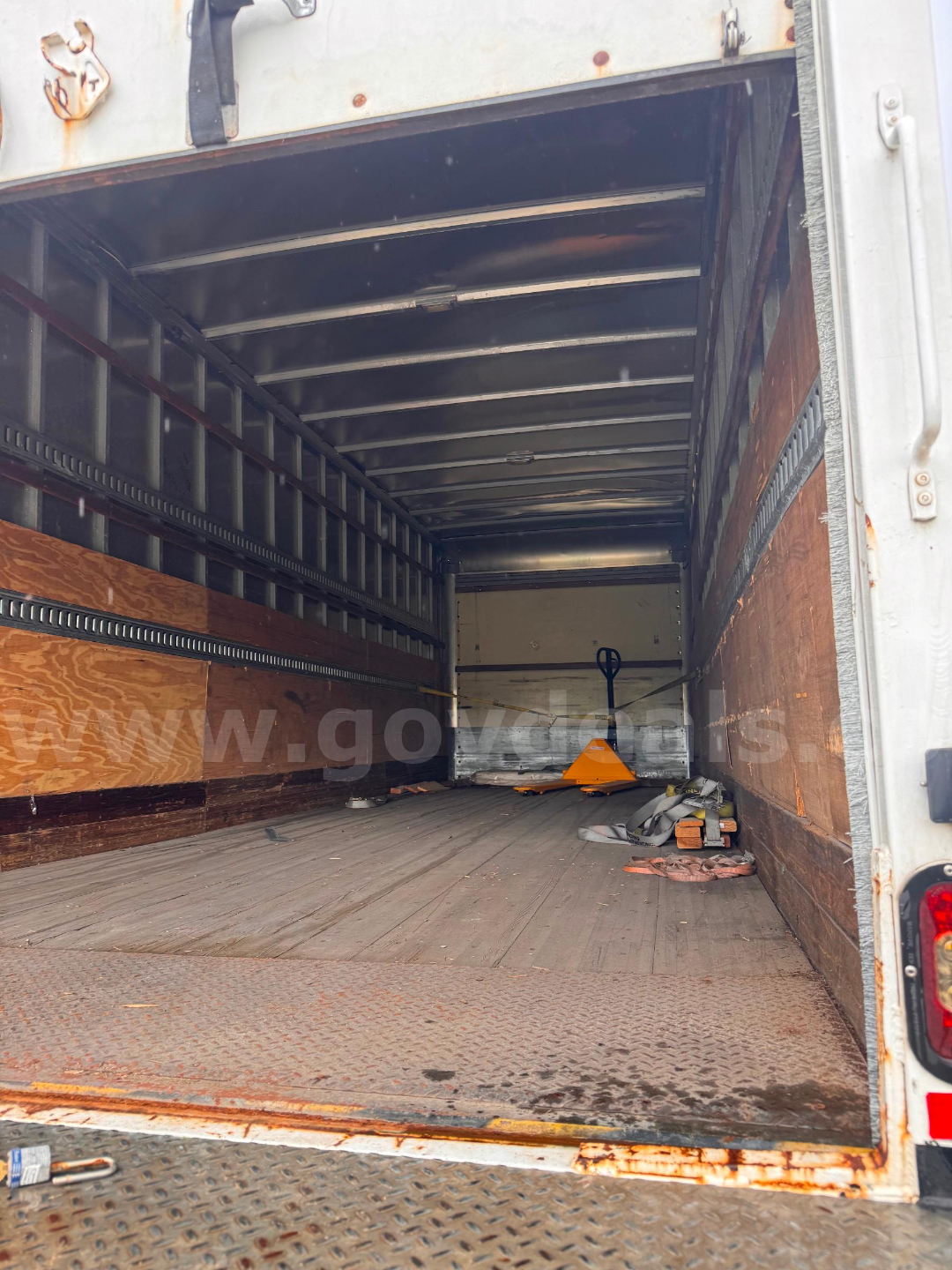 Truck box interior showing empty cargo area with wood side panels and metal kept rails.