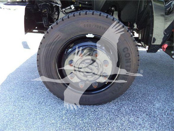 Truck wheel and tire with steel rim, fender and undercarriage visible. Text on tire sidewall includes numbers like 225/70R. Brand markings and lug nuts are visible.