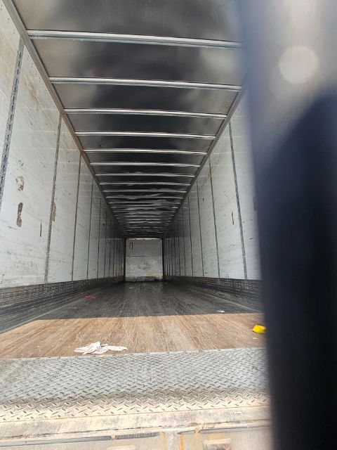 Trailer interior with metal sidewalls, empty cargo space, wood floor and diamond plate threshold.