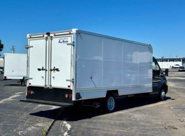 Box truck rear and side view showing white cargo box and rear double doors with black latches; small brand label on left door.