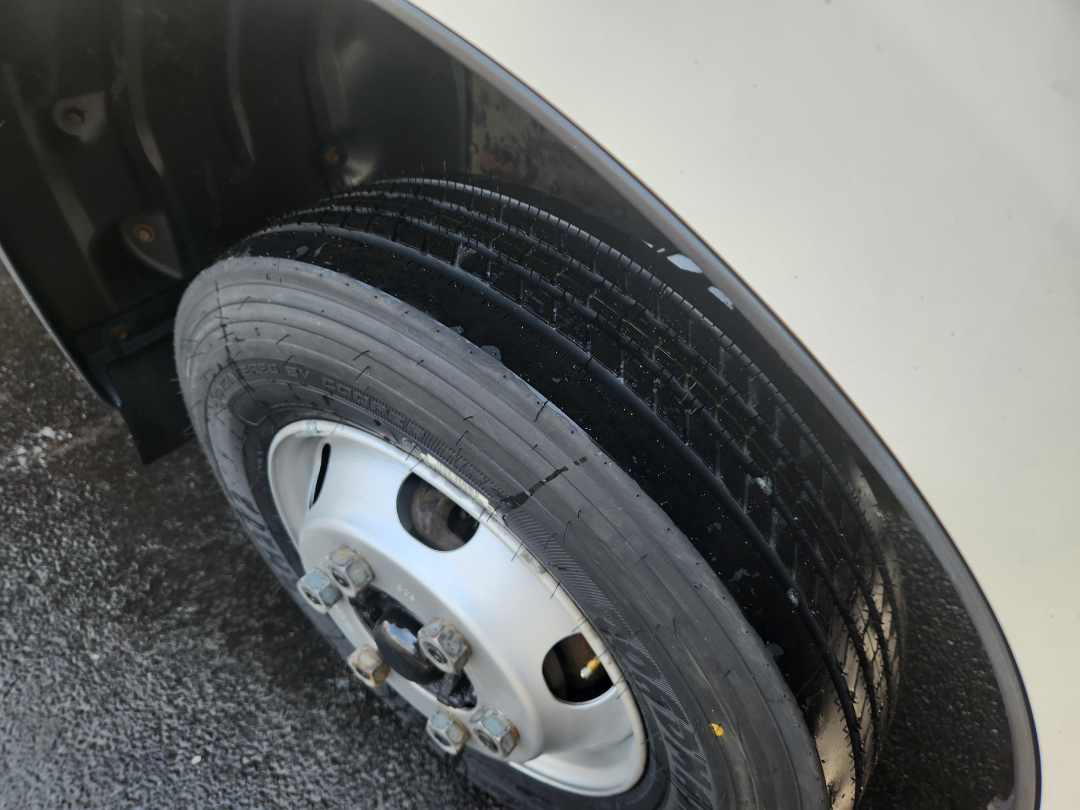 Front right wheel of a 2017 Hino 155 box truck showing wheel and tire with gloss black rubber and steel rim.